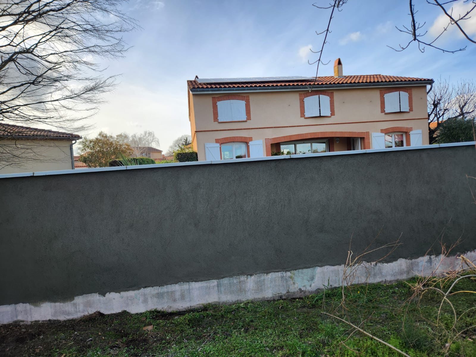 Mur de clôture enduit, façade rénovée à l'arrière